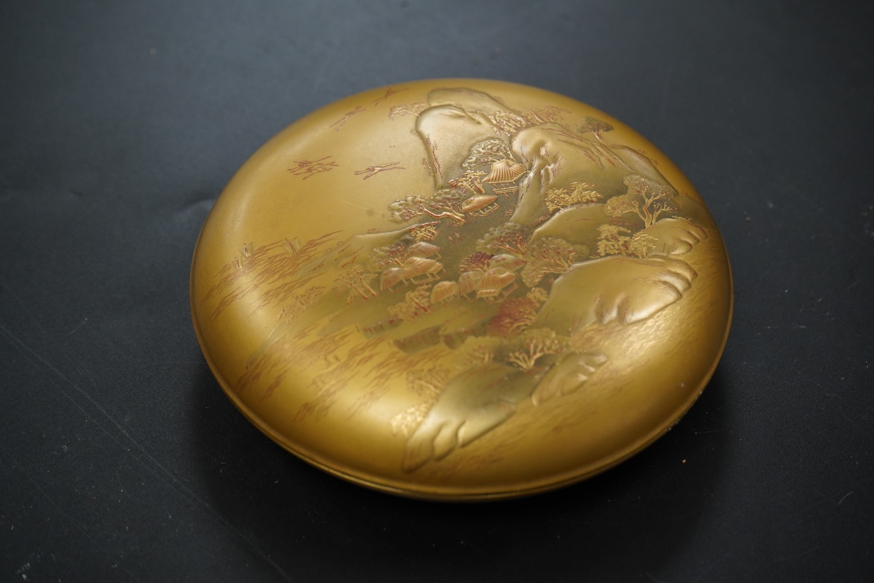 A Japanese circular gilt lacquer box decorated in relief, with paperwork, 10cm in diameter